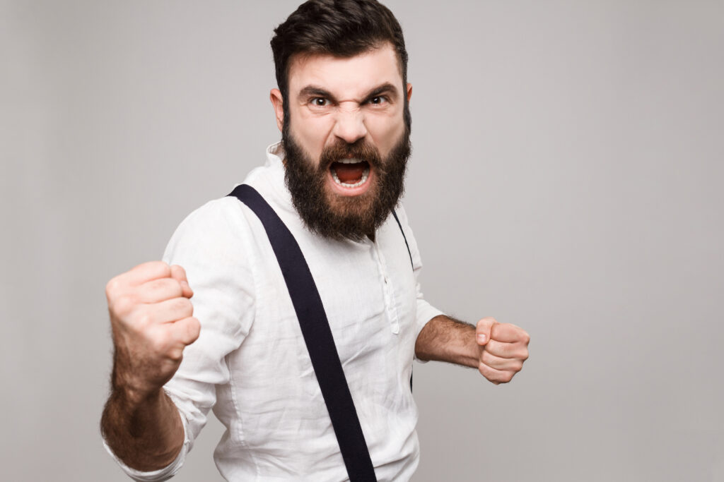 Angry rude young handsome man shouting over white background.